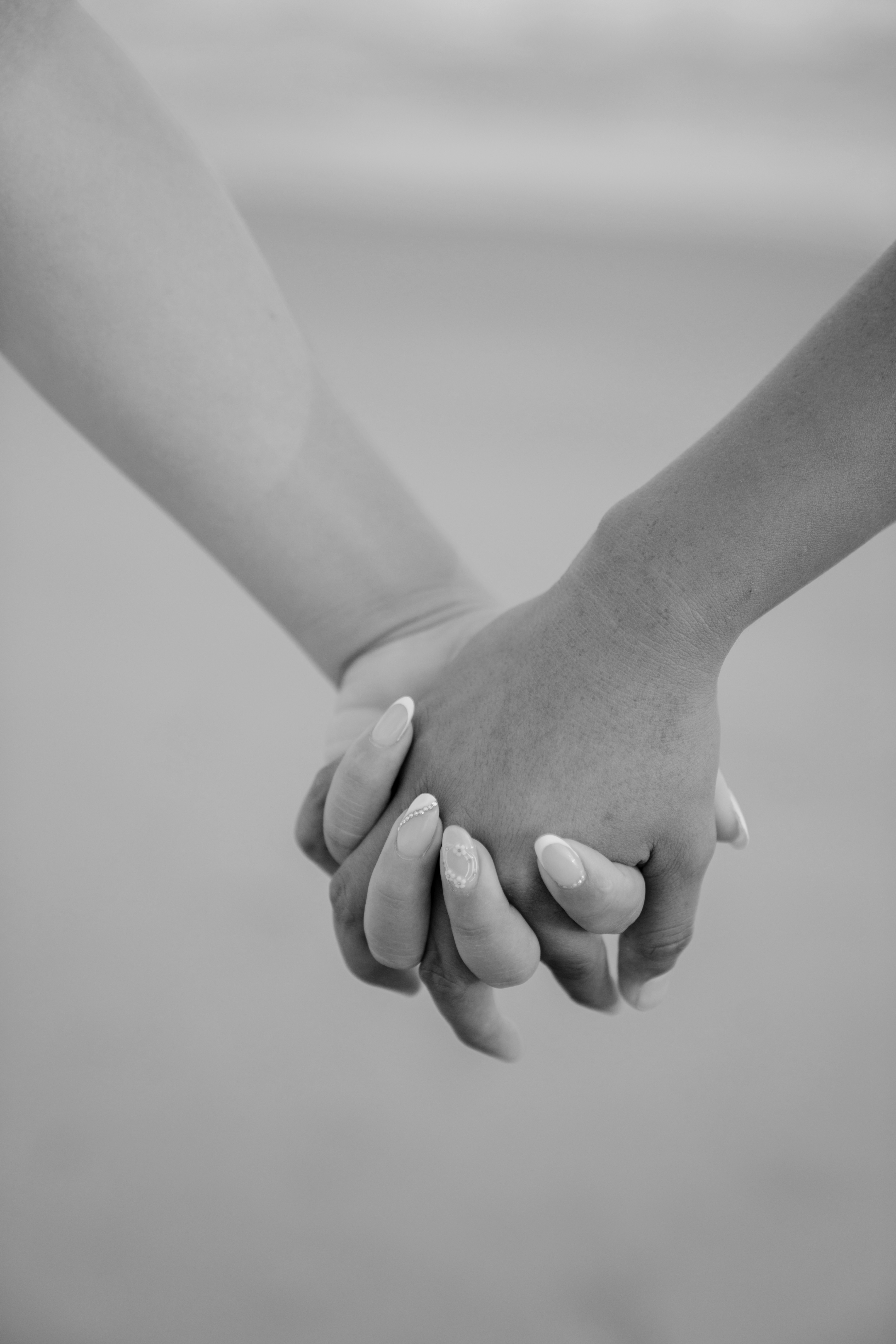 Retrato romántico en blanco y negro, novio besando tiernamente la mano de su prometida frente al mar.