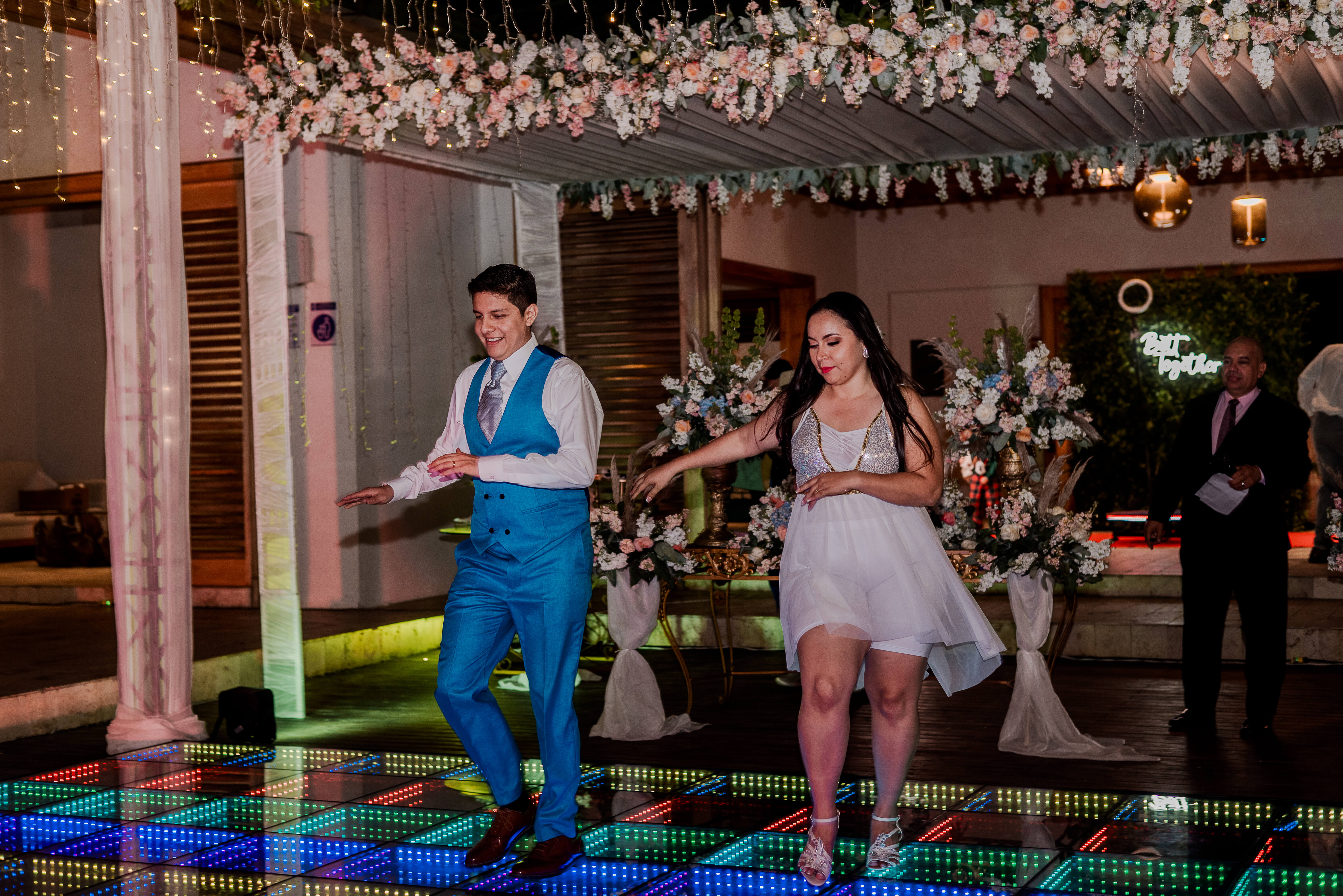 Kattya y Freddy bailando en la pista junto al corte de honor durante la fiesta de su boda.