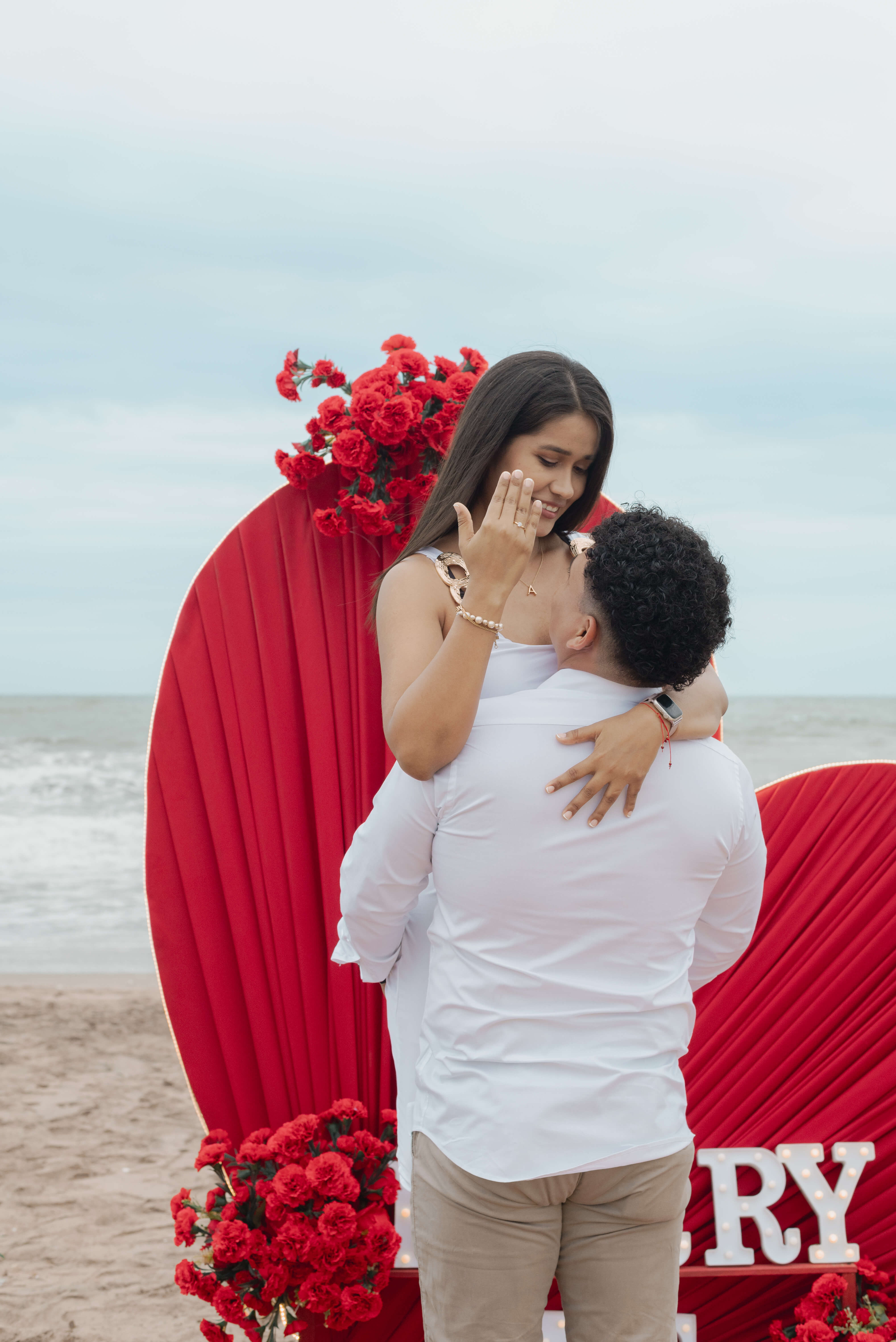 Jean y Andrea se encuentran frente al escenario decorado para su pedida de mano junto al mar.
