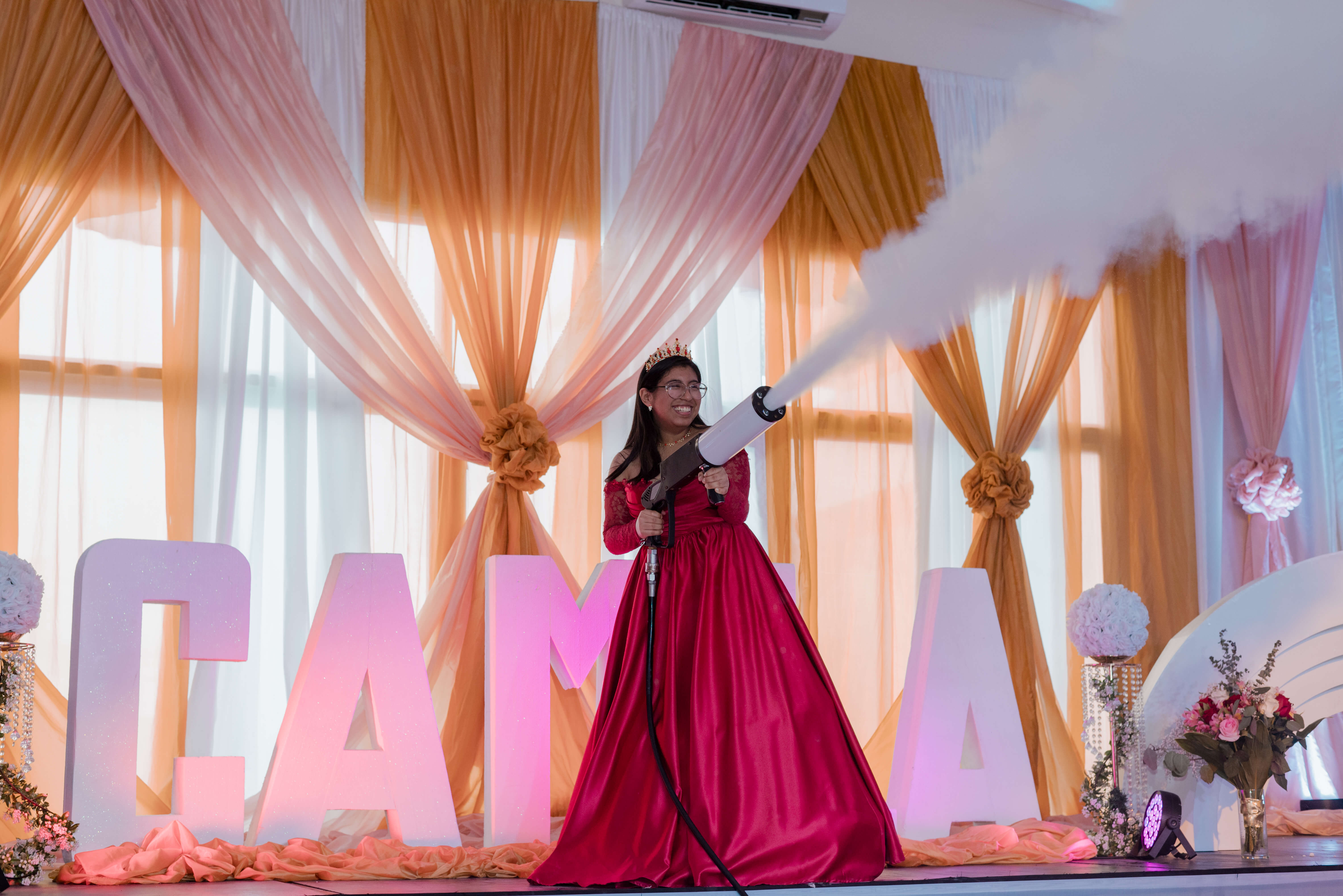 Quinceañera Camila sonriendo feliz con una pistola de humo en el Hotel Laverdy.