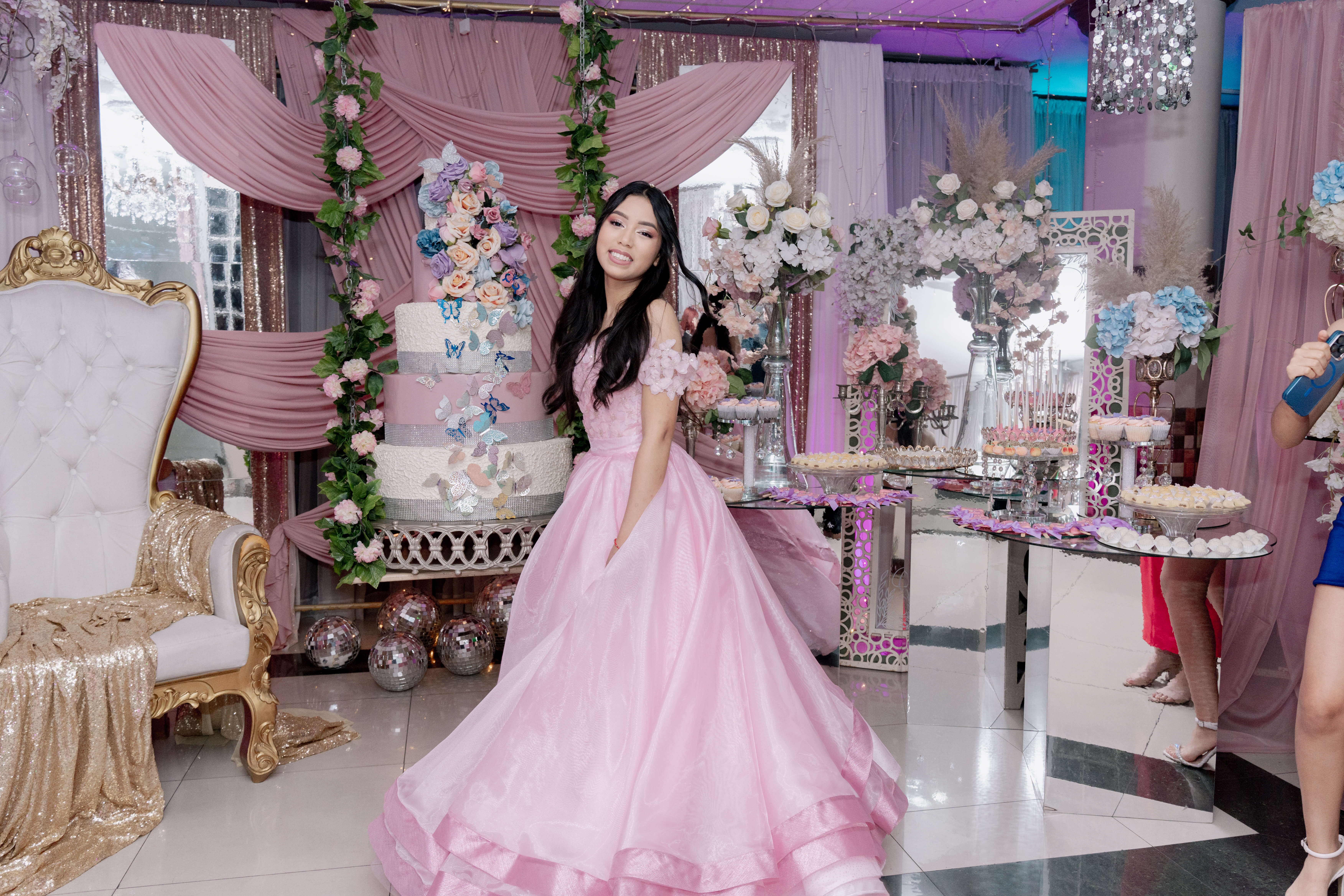Vista de cuerpo entero de María Paula posando con su vestido de gala junto a la decoración principal del evento.